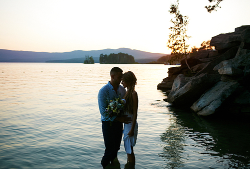 Young lovers standing in water at sunset