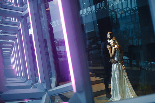 Happy bride and groom standing inside modern building