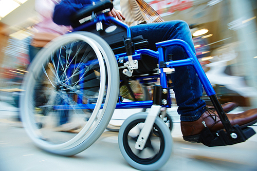 Invalid man in wheel-chair being pushed by caregiver