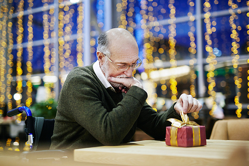 . senior man looking at gift-box on table