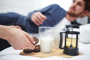 Human hand taking chocolate biscuit sandwich from wooden tray