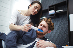 Skeptical man frowning face while his wife showing him pregnancy test