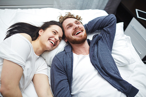 Joyful and carefree couple laughing while relaxing in bed