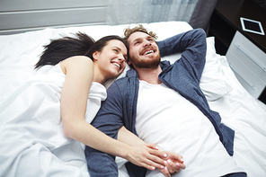 Joyful young couple relaxing in bed