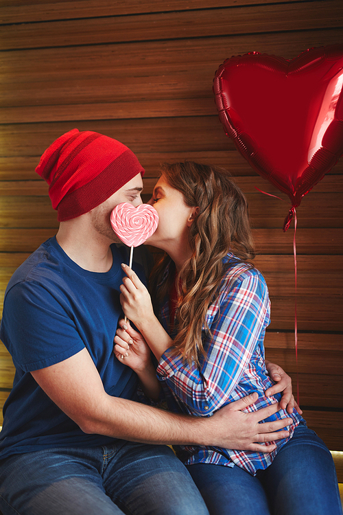Amorous dates with heart-shaped candy and balloon kissing in embrace