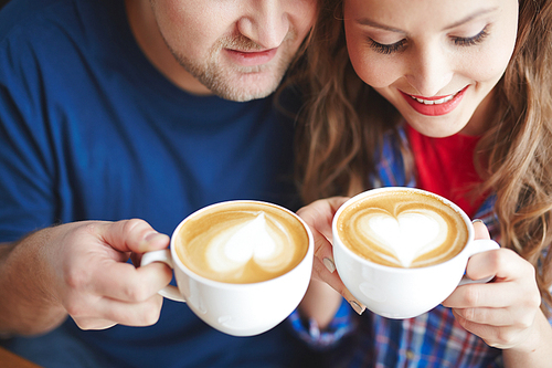 Young couple drinking cappuccino from porcelain cups