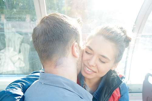 Young couple embracing and amorous man kissing his girlfriend on her cheek