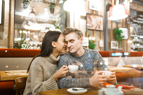 Young affectionate couple relaxing in cafe by cup of coffee