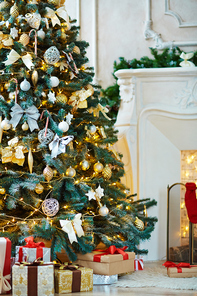 Christmas tree decorated with bubbles, bows and stars and heap of gifts near by