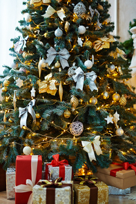 Christmas tree decorated with toys and garlands and packages with presents near by