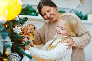 Affectionate grandmother and granddaughter decorating firtree for xmas night