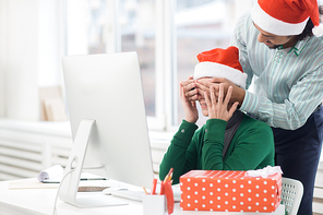 Businesswoman trying to guess who covering her eyes by hands to make her xmas surprise