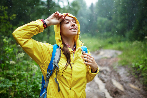 Young woman with backpack enjoying rainy weather