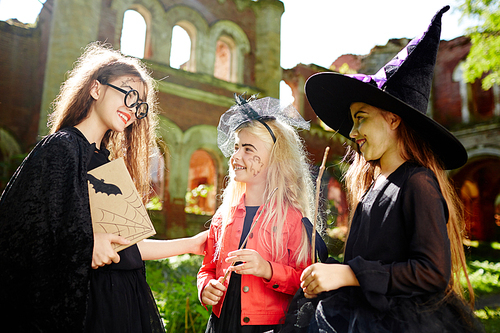 Friendly companions in witch attire interacting at halloween party on sunny day