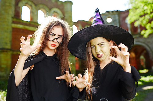 Frightening little witches in black warlocks at halloween party