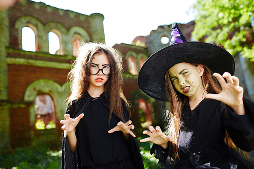 Two angry witches showing frightening hand gesture to you