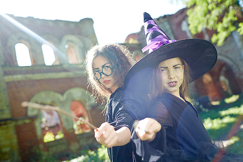 Spooky witches in halloween attire pointing at you by their magic sticks