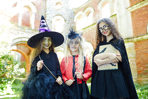 Smiling witches with halloween magic symbols gathered for having fun and playing tricks