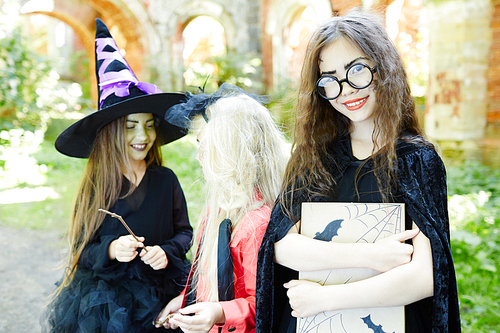 Happy girl with book and her friends on background enjoying halloween