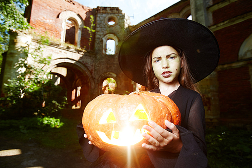 Halloween little girl in black hat and warlock holding jack-o-lantern