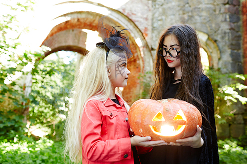 Blond and brunette girls sharing halloween jack-o-lanterhn