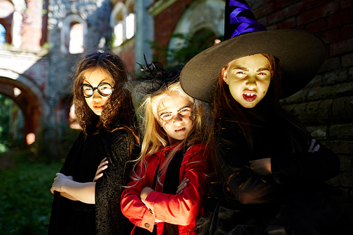 Frightening girls leaning against wall of building on halloween evening outdoors