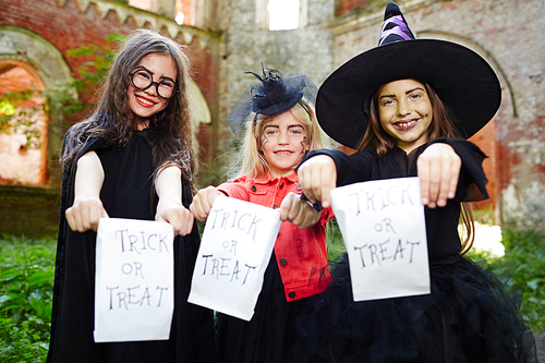 Happy girls with paper packets asking for traditional halloween treats