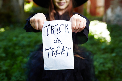 Trick-or-treat paper sack held by halloween girl in traditional attire