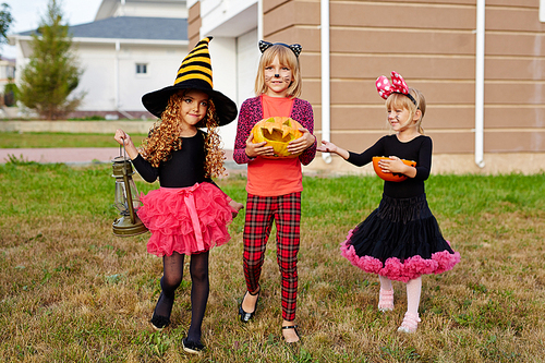 Halloween kids with treats walking down lawn in the yard after trick-or-treat fun