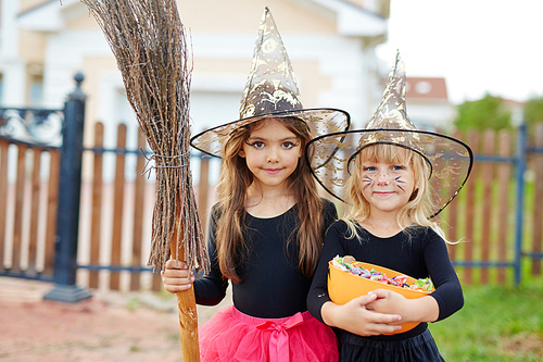 Cute little witches with broom and treats on background of house