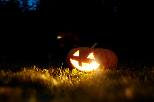 Burning jack-o-lantern on grass in halloween night