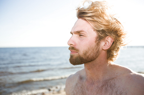 Restful young man enjoying solitude by seaside on summer evening