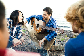 Friendly guys gathered by seaside on summer evening