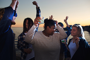 Friends with drinks relaxing at disco party on the beach