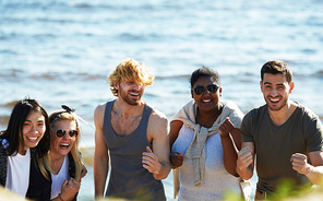 Joyful friends enjoying each others company while having beach party, they  with toothy smiles and dancing, group portrait