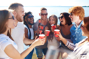 Ecstatic friends cheering up with drinks on the beach