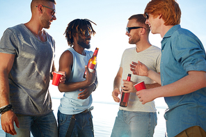 Happy guys in sunglasses having beer refreshment on hot day