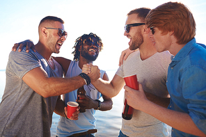 Friendly guys having fun on summer weekend by seaside