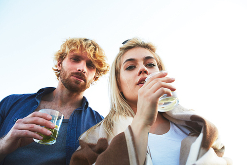 Low angle view of confident young couple  while enjoying refreshing mojito cocktails outdoors, waist-up group portrait