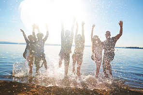 Carefree guys and girls dancing in water at beach party