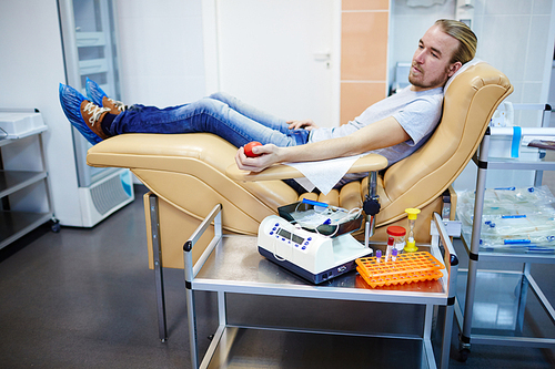 Young man sitting in armchair at hemotransfusion station