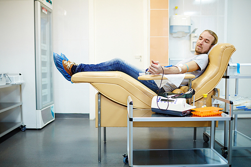 Young volunteer donating his blood in hemotransfusion station