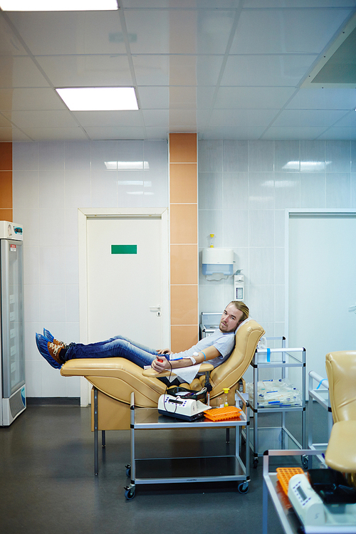 Guy sitting in armchair and giving his blood