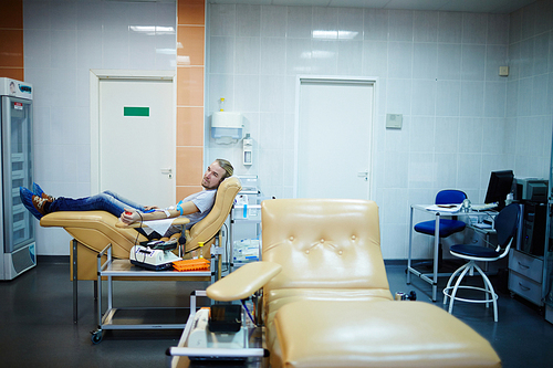 Young volunteer sitting in clinic room during transfusion of blood