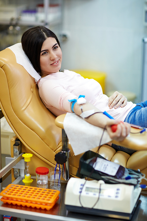 Smiling girl lying in armchair during hemotransfusion