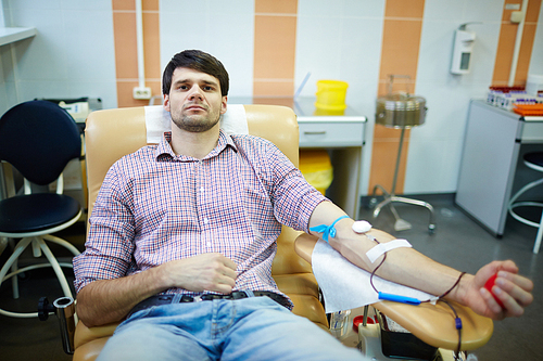 Man with dropper donating his blood in hospital