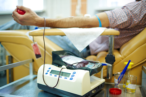 Equipment for donating blood and human lying in armchair on background