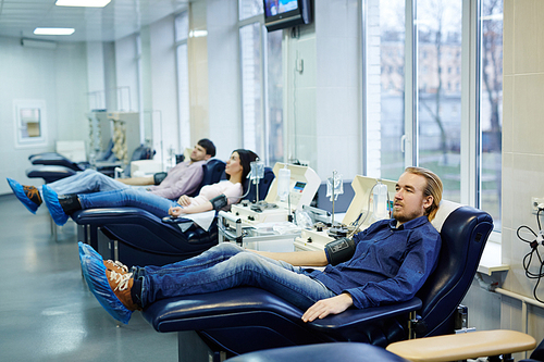 Row of donors checking blood pressure in hemotransfusion clinic