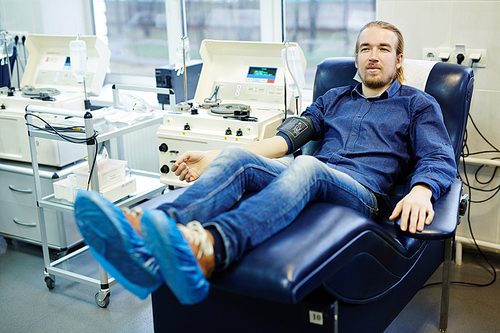 Donor of blood sitting in armchair by platelets blood separation machine