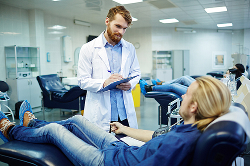 Young man in armchair talking to clinician